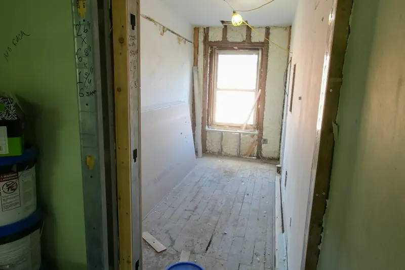 A room under construction with unfinished flooring, walls and door.